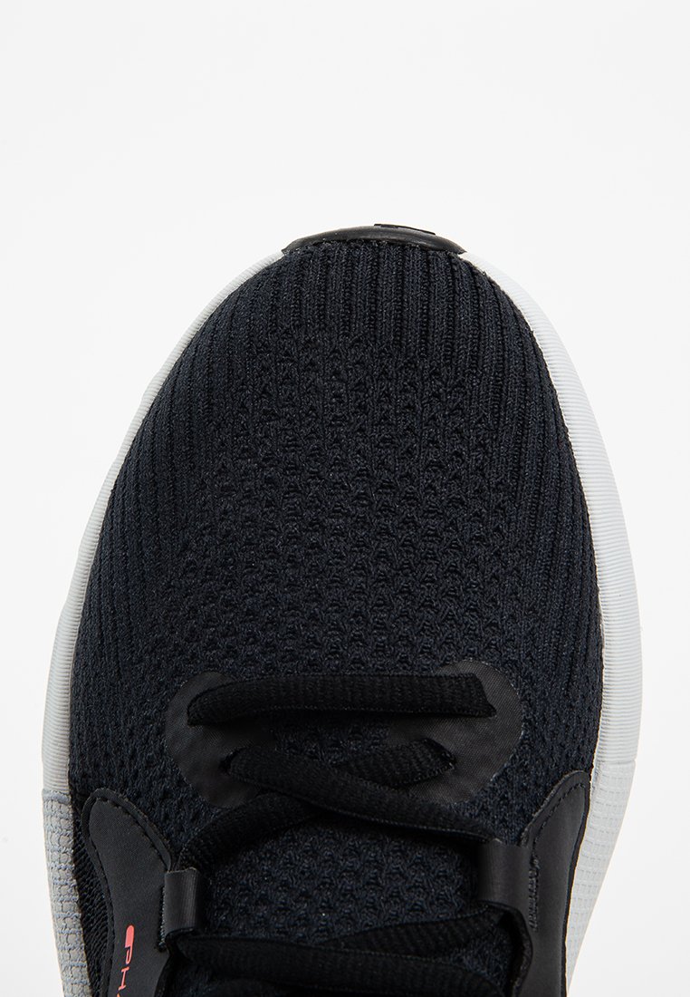 Zapatilla deportiva negra con una parte superior de punto texturizado, cordones negros y una suela blanca. Presenta un acento gris en el costado y un diseño de puntera redonda.