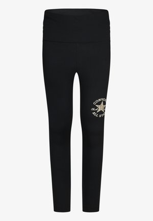 Leggings negros fabricados con material elástico, con una cintura ancha y un diseño de logo dorado en el muslo derecho.