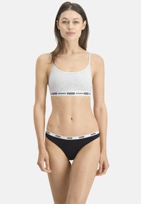 Soutien-gorge de sport gris avec une bande blanche portant l'inscription "PUMA" et bas de bikini noir avec une bande similaire. Les deux sont fabriqués en tissu élastique en mélange de coton.