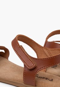 Sandali in pelle marrone con due cinturini regolabili, una morbida fodera interna e una soletta testurizzata e imbottita per il massimo comfort.