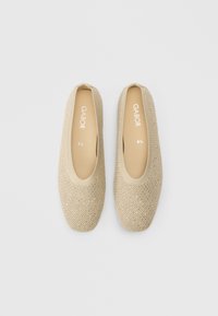 Beežid libisemiskindlad kingad tekstuurse kudumülaosaga, ümmarguse varbaosaga ja polsterdatud tallaga, mille sees on trükitud brändinimi „Gabor“.