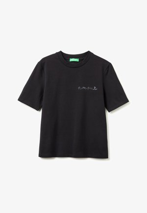T-shirt noir à manches courtes et col rond avec un petit texte en cursive "amour" brodé sur la poitrine gauche et une étiquette verte à l'intérieur du col.