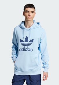 Hoodie azzurro chiaro con logo Adidas navy e design a tre strisce sulla parte anteriore. Presenta una tasca a marsupio e cappuccio con cordini.