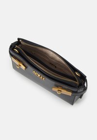 Borsa a mano in pelle nera con hardware dorato, chiusura con zip e scomparti doppi. Interno foderato in tessuto beige, con diverse tasche.