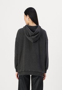 Dunkelgrauer übergroßer Kapuzenpulli mit gefütterter Kapuze, gerippten Bündchen und lockerer Passform, aus weichem Material mit leicht strukturierter Oberfläche.