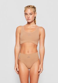 Sport-BH und hochgeschnittene Slip-Set in hellem Beige, aus glattem Material. Verfügt über minimale Nähte und ein Adidas-Logo auf der Vorderseite.