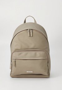 Beige nylonrygsæk med afrundet top, dobbelte lynlåse, frontlomme og en lille logoetiket. Glat tekstur og enkelt, funktionelt design.