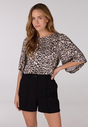 Leopardprint, kortemouwen top in beige en zwart; gecombineerd met hoge zwarte shorts met een knoop aan de voorkant en een geplooid ontwerp.