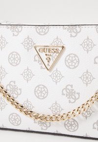Witte handtas met een gestructureerd patroon, voorzien van een driehoekig gouden logo en een gouden kettinghengsel. Rechthoekige vorm met slanke designelementen.
