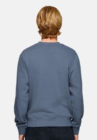 Crewneck sweatshirt i dæmpet blå. Blødt stof med ribbede manchetter og kant, der har et klassisk bagside-design uden synlige logoer.