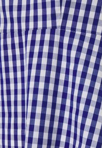 Modrý a bílý kostkovaný látkový vzor se viditelnými švy a drobnými záhyby, které ukazují kostkovaný vzor.