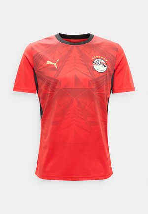 Raudonas futbolo marškinėlis su juodu apykakle, Egipto futbolo federacijos logotipu su žvaigždėmis, auksiniu Puma logotipu ir geometriniu raštu priekyje.