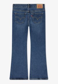 Μπλε τζιν παντελόνι καμπάνα, με μέση μέτριου ύψους, δύο πίσω τσέπες με ραφές και καφέ ετικέτα στη ζώνη της μέσης στο πίσω μέρος.