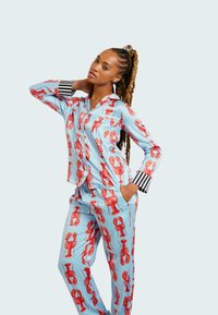 Ljusblå pyjamas set med en hummertryck i rött. Skjortan har krage och knappstängning, medan byxorna har resårmidja med fickor.