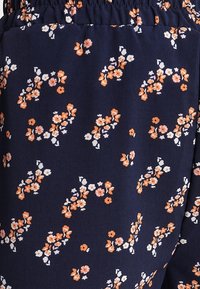 Navy fabric with a floral pattern in white and orange tones. Features a textured surface and an elastic waistband for comfort.