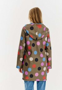 Zielony płaszcz przeciwdeszczowy z kapturem w wielokolorowe kropki w kolorach czerwonym, niebieskim, różowym, czarnym i białym; posiada długie rękawy i prosty krój.