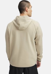 Sudadera beige claro con capucha ajustable, mangas largas y dobladillo redondeado. Fabricada en una tela suave con una textura lisa y costuras mínimas.