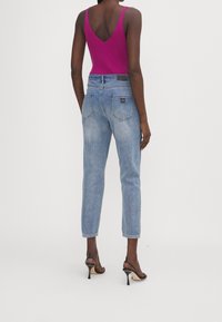 Přiléhavý magenta žebrový top s véčkovým výstřihem, kombinovaný se světle modrými vysokými džínami, které mají čistý design a minimální kovové detaily.