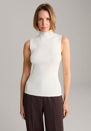 White, ribbed, sleeveless turtleneck top with fitted design. Soft texture complements brown, loose-fitting trousers. Simple and modern style.