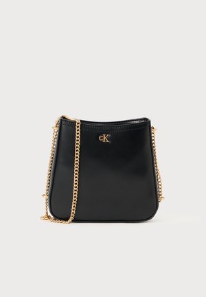 Geantă din piele neagră cu o curea din lanț aurit, având o formă rotundă și un logo cK embosat pe față. Textură netedă, design minimal.
