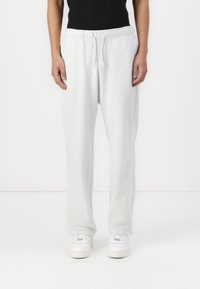 Lysegrå sweatpants lavet af blødt stof, med en elastisk talje med snøre og en afslappet pasform. Hvide sneakers inkluderet.