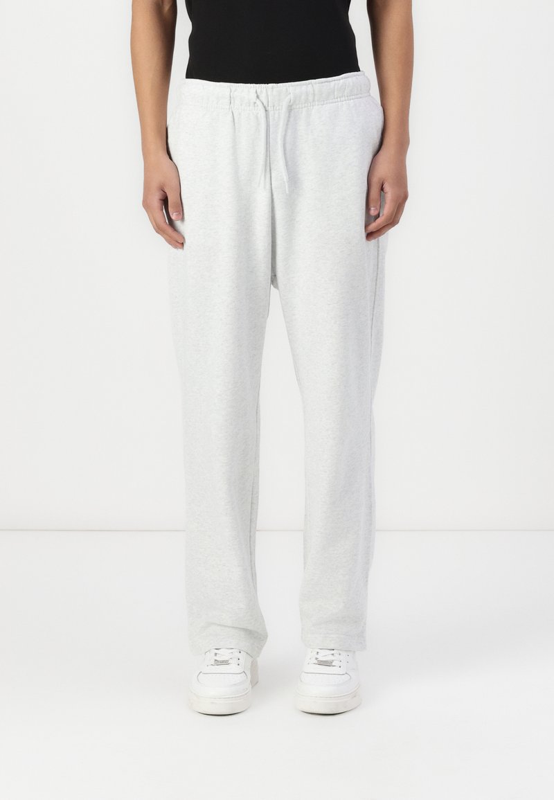 Lysegrå sweatpants lavet af blødt stof, med en elastisk talje med snøre og en afslappet pasform. Hvide sneakers inkluderet.