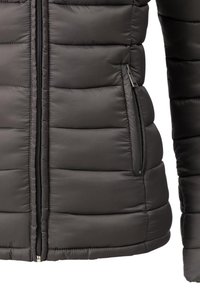 Gros plan d'une veste noire matelassée avec une fermeture éclair frontale et une poche latérale zippée sur un tissu rembourré.