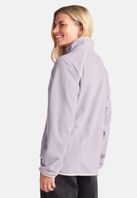 Light purple fleece jacket with high collar, contrasting cream stitching, and relaxed fit. Smooth texture and long sleeves.