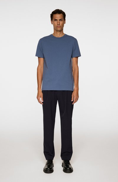 T-shirt en coton bleu associé à un pantalon noir ajusté. Le t-shirt présente un col rond, des manches courtes et une coupe droite. Chaussures noires.