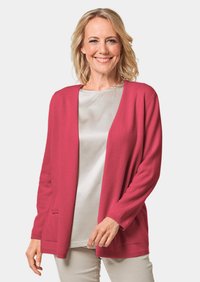 Roze gebreide cardigan met een open voorkant, lange mouwen en twee zakken. Draagt over een licht satijnen top. Zuivere textuur, casual ontwerp.