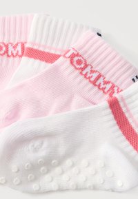 Trois chaussettes basses pliées, roses et blanches, avec des rayures roses et des grips texturés sous la semelle.