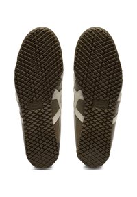 Brązowe sneakersy z teksturowaną gumową podeszwą, z falistym wzorem, białymi akcentami i wyraźnym logo na pięcie.