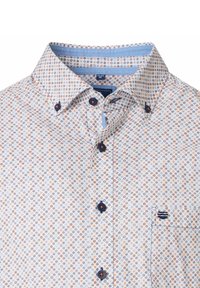 Witte overhemd met kleine oranje en blauwe cirkelpatronen, blauwe knopen en een klein geborduurd marineblauw logo op de borstzak.