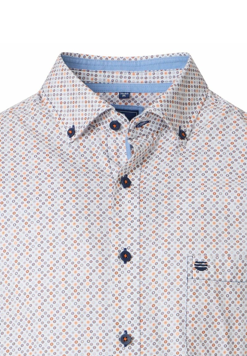 Witte overhemd met kleine oranje en blauwe cirkelpatronen, blauwe knopen en een klein geborduurd marineblauw logo op de borstzak.