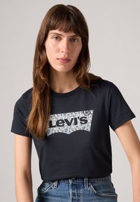 T-shirt en coton noir avec un design de logo floral blanc de Levi's. Manches courtes et col rond classique. Tissu texturé.