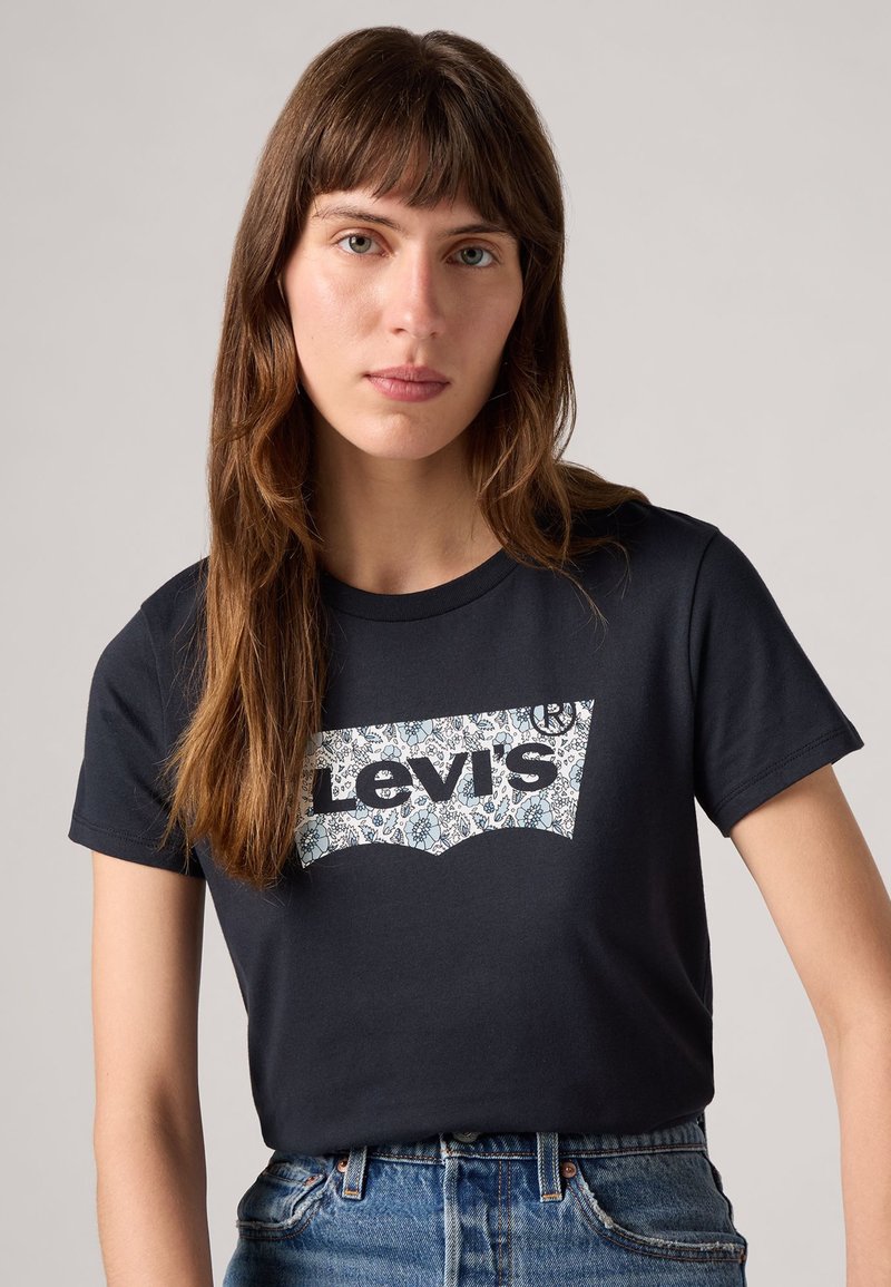Schwarzes Baumwoll-T-Shirt mit einem weißen Blumen-Logo-Design von Levi's. Kurze Ärmel und klassische Rundhalsausschnitt-Form. Strukturierter Stoff.