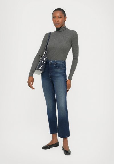 Grå høyhalset genser, høyt midje mørke jeans med lett falming, kombinert med svarte ballerinasko og en liten marineblå veske. Enkel, tettsittende design.