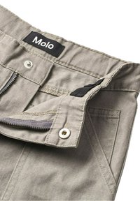 Beige canvas broek met een ritsvlieg, knoopsluiting en verstelbare zwarte bandjes in de tailleband. Voorzien van twee voorzakken.