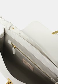 Borsa a mano in pelle bianca con una texture liscia, dotata di una tasca con zip e dettagli in hardware dorato. L'interno è realizzato in un tessuto chiaro e liscio.