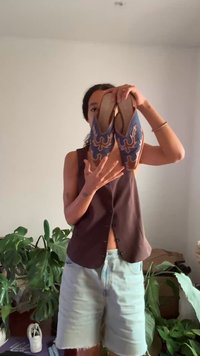 Plave natikače s smešnim detaljima u smešnim nijansama, sa složenim vezom, okruglim vrhom i glatkom kožnom teksturom, koje drži osoba.