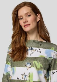 Gestreiftes Langarmoberteil in Grün und Weiß mit Sternmustern und abstrakten Designs; lockere Passform mit weitem Ausschnitt und weichem Textil.