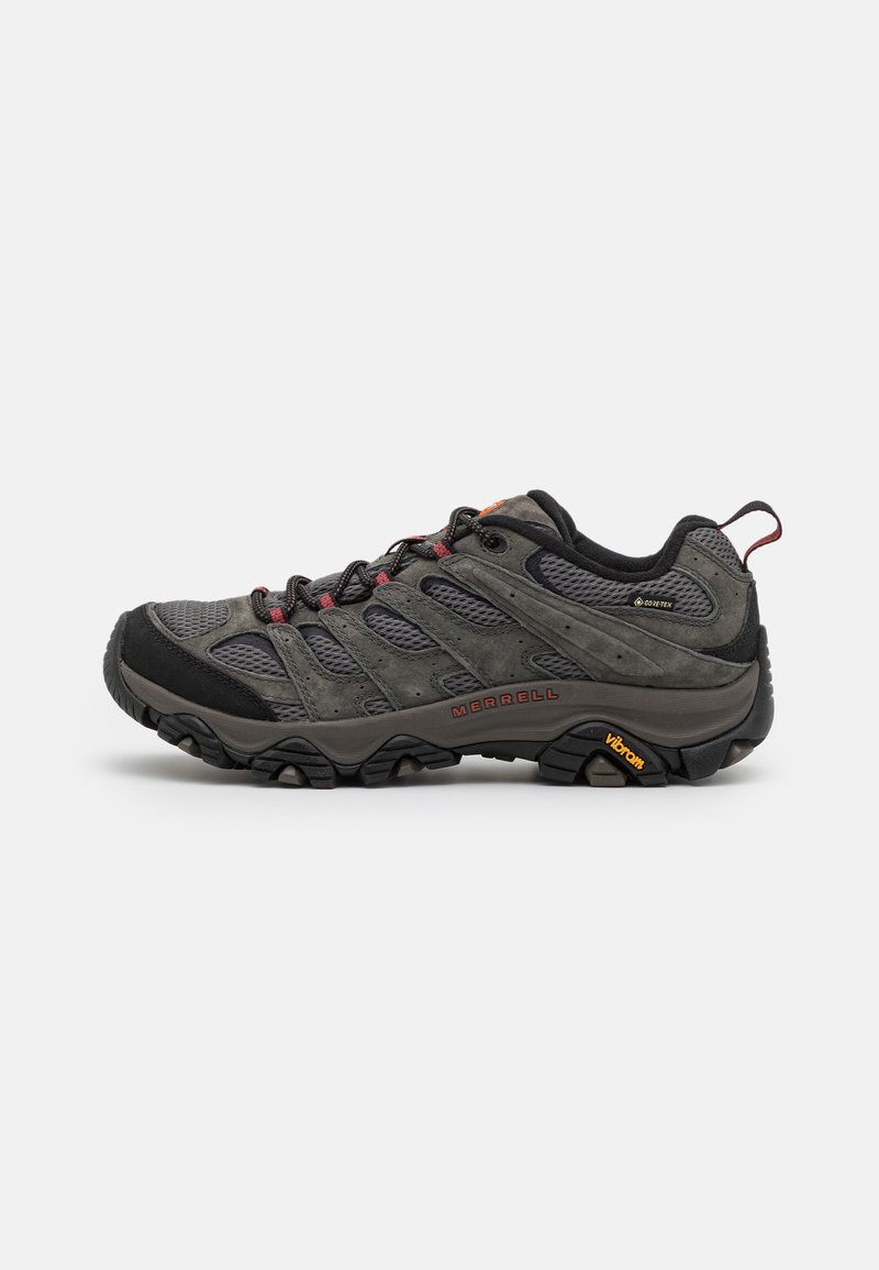 Grå vandresko med mesh og ruskindsmaterialer, gummisål, snøresystem og røde accenter. Har Vibram-branding på sålen.