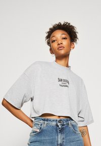 Gray cropped t-shirt with short sleeves, featuring black text "SAN DIEGO 1995 CALIFORNIA" in the center, paired with high-waisted denim shorts.
