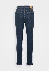 Mörkblå jeans med smal passform, tillverkade av denim. Har bakfickor och en bakre läderlapp vid midjan. Klassisk femficksdesign.