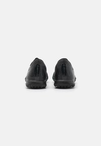 Black athletic shoes with textured upper, distinctly shaped heel, and rugged outsole. Features a logo at the heel and contrasting blue accents.