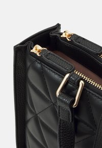 Torebka z pikowanej czarnej skóry z złotymi akcentami i zamknięciem na zamek. Teksturowane detale oraz elegancki design z widocznością wnętrza.