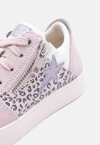 Ανοιχ τό ροζ αθλητικό παπούτσι με πλαϊνή επιφάνεια με σχέδιο λεοπάρδαλης, μοβ αστέρι, ασημένιο φερμουάρ και ροζ κορδόνια που ταιριάζουν, πάνω σε λευκή σόλα.