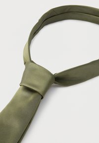 Λαδί μεταξωτή γραβάτα δεμένη με ένα απλό κόμπο σε λευκό φόντο.