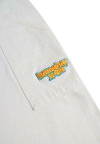 Camicia di cotone bianca con taschino sul petto sinistro e ricamo multicolore "homeboy Kira". Tessuto testurizzato con sottili righe.