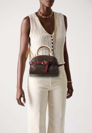 Brown leather bag with red accent and bow detail. Features a structured shape, top handle, and removable shoulder strap.